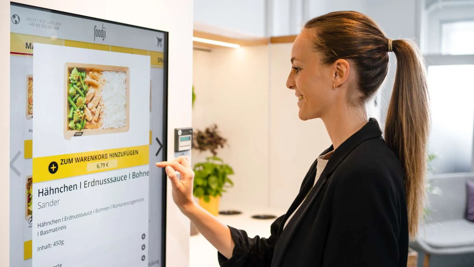 A woman at the Foodji vending machine, deciding what healthy meal to pick.